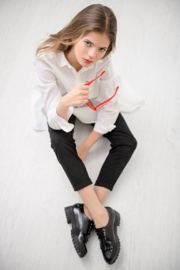 Sevimli kız genç odası katta oturan güneş gözlüğü ile portresi. Modern bir genç nesil için gözlük. Güzellik, moda.
