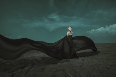 Tam uzunlukta portre güzel bir Gotik kadının uzun siyah elbise poz açık. Güzellik, moda.