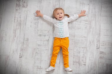 Neşeli bir kız yerde yatıyor. Çocuklar için moda.