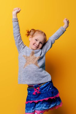 Çocuk moda. Parlak sarı arka plan üzerinde poz örme giyim eşyası şirin altı yaşında bir kız portresi. Bahar, kış modası. Kız mutlu çocuk.