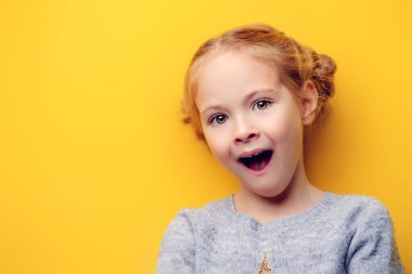 Yakın çekim portre fotoğraf makinesi vasıl surat duygusal bir kız. Stüdyo sarı arka plan üzerinde vurdu. Çocukluk kavramı.