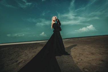 Tam uzunlukta portre güzel bir Gotik kadının uzun siyah elbise poz açık. Güzellik, moda.