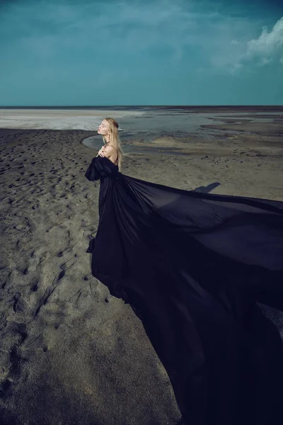 Tam uzunlukta portre güzel bir Gotik kadının uzun siyah elbise poz açık. Güzellik, moda.