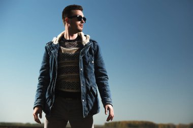 Bir ceket ve güneş gözlüğü takan yakışıklı acımasız bir adam. Moda erkekler için. Bahar, kış.