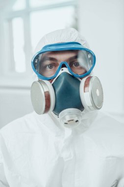 Coronavirus veya COVID-19 konsepti. Koruyucu PPE takım elbiseli bir doktorun portresi, beyaz arka planda gözlük ve solunum maskesi..