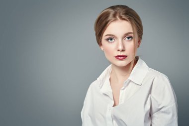 Sarışın ve doğal makyajlı güzel bir genç kadının portresi. Stüdyo görüntüsü gri arka planda. Güzellik endüstrisi.