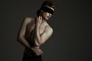 Art portrait of a handsome athletic young blindfold man with perfect muscular body. Sports and bodybuilding. Men's beauty and health. Copy space. clipart