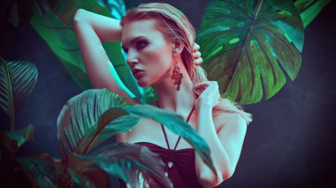 Islak saçlı güzel ateşli kadın tropikal bitkilerin arasında duruyor. Güzellik, moda ve kozmetik konsepti. Tropikal ülkelerde tatil.