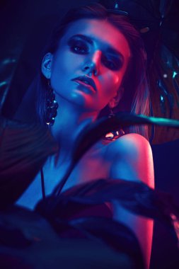 Palmiye yapraklarının arasında ıslak saçlı güzel bir tropikal kadının portresi. Güzellik, moda ve kozmetik konsepti. Tropikal ülkelerde tatil.