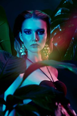 Palmiye yapraklarının arasında ıslak saçlı güzel bir tropikal kadının portresi. Güzellik, moda ve kozmetik konsepti. Tropikal ülkelerde tatil.