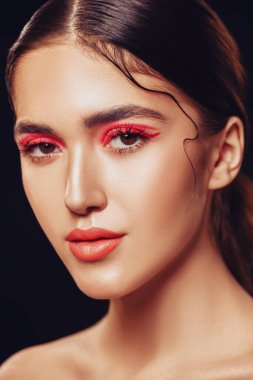 Makyaj ve kozmetik konsepti. Parlak makyajlı ve gözlerinde kırmızı oklar olan güzel bir kızın portresi. Güzellik, moda. Siyah arkaplan. 