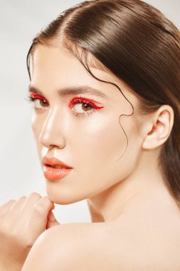 Makyaj ve kozmetik konsepti. Parlak makyajlı ve gözlerinde kırmızı oklar olan güzel bir kızın portresi. Güzellik, moda.