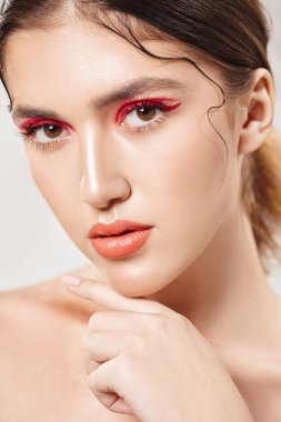 Makyaj ve kozmetik konsepti. Parlak makyajlı ve gözlerinde kırmızı oklar olan güzel bir kızın portresi. Güzellik, moda.