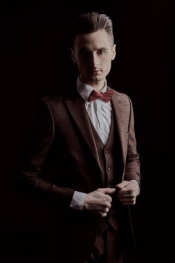 Siyah arka planda zarif bir takım elbise ve papyon giymiş yakışıklı bir adamın portresi. İş stili. Erkek modası.
