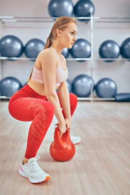 Profesyonel spor ve sağlıklı yaşam tarzı. Güzel kız sporcu bir su ısıtıcısı ile güç egzersizleri yapıyor. Ağırlık kaldırmak, vücut geliştirmek..