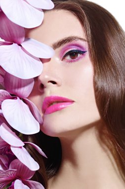 Orkide çiçekleri olan güzel romantik bir kadının yakın plan portresi. Makyaj ve makyaj malzemeleri. Güzellik ve sağlık hizmetleri.