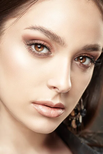 Make-up and cosmetics. Close-up portrait of a beautiful brunette girl with brown evening make-up.