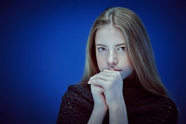 Kameraya bakan güzel, modern bir genç kızın portresi. Koyu mavi arkaplanda stüdyo portresi.