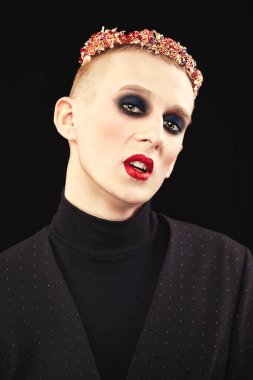 Siyah elbiseli ve açık renk şapkalı kadın makyajlı genç bir adamın portresi. Avangart.