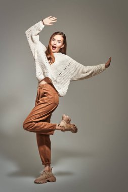 Moda fotoğrafı. Modern gündelik giysiler içinde, stüdyoda hareket halinde poz veren güzel bir kız. Tam boy portre. Mutluluk ve başarı kavramı.  