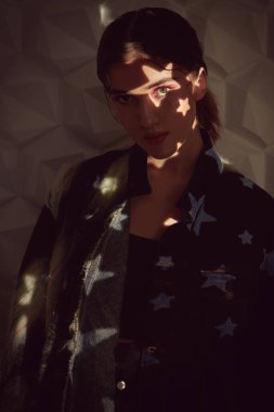 Moda fotoğrafı. Güzel, modaya uygun bir model, yıldızlı beyaz bir arka planda şık kıyafetler giyiyor. Stüdyo resmi. 