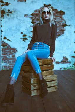 Uzun boylu, sıradan kıyafetler ve yüksek topuklu çizmeler giyen sarışın bir kızın portresi. Güzellik, moda. Modern pin-up biçimi.