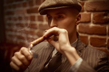 Karanlıkta dalgın dalgın oturup puro içen yakışıklı bir adamın portresi. Lüks bir yaşam tarzı. Retro tarzı. Mafya ve suç dünyası, dedektif..