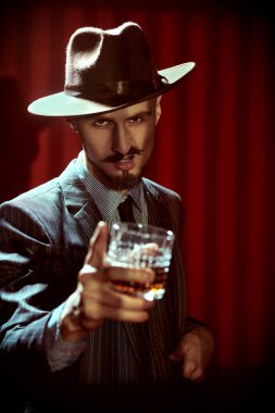 Zarif klasik takım elbiseli yakışıklı bir adamın viski içen portresi. Retro tarzı. Lüks bir yaşam tarzı. Erkek güzelliği, moda.
