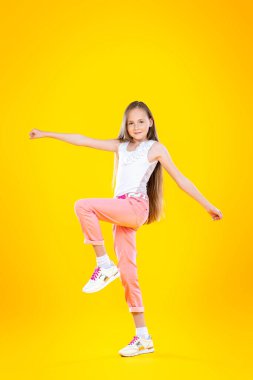 Sarı arka planda hareketli gülümseyen bir kızın tam boy portresi. Güzellik, yaz, moda. Eğitim.