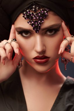 Arap güzelliği, moda. Geleneksel makyajlı, siyah tesettürlü ve siyah arkaplanlı güzel bir doğulu kadının portresi. Makyaj ve kozmetik. 