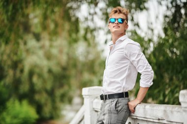 Yakışıklı genç adam şehirde geziniyor ve gülümsüyor. Yaz modası. Yaz tatili ve tatil.