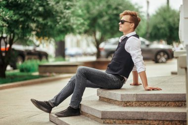 Yakışıklı genç adam şehirde geziniyor ve gülümsüyor. Yaz modası. Yaz tatili ve tatil.