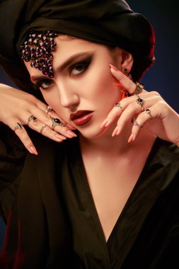 Arap güzelliği, moda. Geleneksel makyajlı, siyah tesettürlü ve siyah arkaplanlı güzel bir doğulu kadının portresi. Makyaj ve kozmetik. 