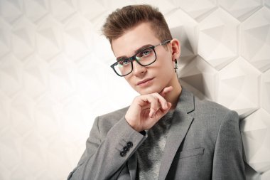 Takım elbiseli ve gözlüklü zeki bir gencin portresi. Stüdyo çekimi. Erkeklerin güzelliği.