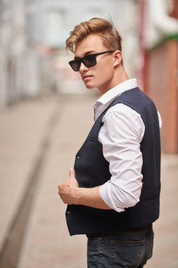 Şehir güvertesinde yürüyen yakışıklı genç adam. Yaz modası. Yaz tatili ve tatil.