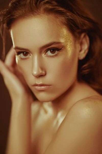 Golden make-up. Close-up portrait of a beautiful young woman with golden make-up. Luxurious style. Cosmetics and make-up concept.