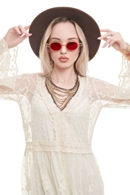 Yaz stili. Açık beyaz dantelli elbise ve güneş gözlüğü takan sarışın güzel bir kızın portresi. Beyaz arkaplanda stüdyo portresi.