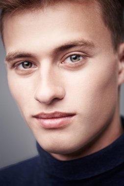 Erkek güzeli. Kameraya gülümseyen sarı saçlı yakışıklı bir gencin portresi. Yakın çekim..