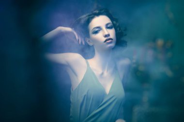 Açık sisli bir odada poz veren muhteşem esmer genç bir kadın. Güzellik, moda. Aşk ve gizem. 