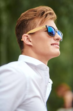 Şehirde gezinen ve gülümseyen yakışıklı bir gencin portresi. Yaz modası. Yaz tatili ve tatil.