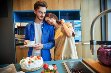 Mutlu genç çift evdeki mutfakta çay içip sohbet ediyorlar. Evin içi, mobilyalar. Mutlu aile kavramı.