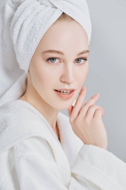 Beyaz bornozlu güzel bir genç kadın portresi ve duş aldıktan sonra saçının etrafına bir havlu. Güzellik, vücut bakımı, kaplıca.