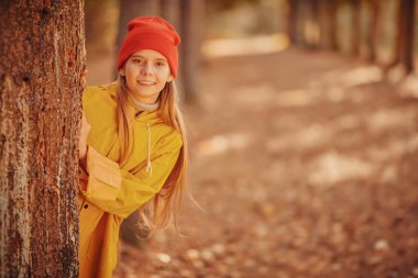 Güzel bir sonbahar ormanında tatlı, gülen bir kız duruyor. Sonbahar mevsimi. 