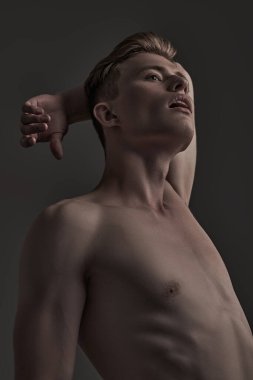 Gri arka planda yakışıklı, kaslı bir adamın portresi. İnsanın güzelliği ve sağlığı. Spor konsepti.