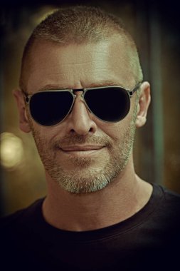 Kısa saçlı ve kıllı, modaya uygun güneş gözlüğü takan yakışıklı ve vahşi bir adamın portresi. Erkekçe. Erkekler için optik.