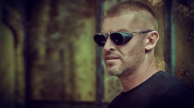 Kısa saçlı ve kıllı, modaya uygun güneş gözlüğü takan yakışıklı ve vahşi bir adamın portresi. Erkekçe. Erkekler için optik.