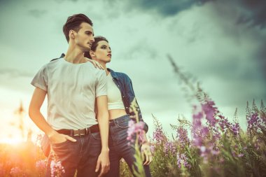 Fırtınalı bir gökyüzüne karşı vadide dikilen kot elbiseli bir çift güzel genç. Güzellik, moda. Denim tarzı. İlişkiler.