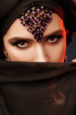 Geleneksel makyaj, siyah tesettüre ve takılara sahip güzel bir doğulu kadının portresi. Makyaj ve makyaj malzemeleri. Arap güzelliği, moda. 