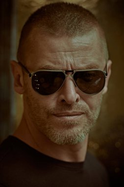 Yakışıklı, vahşi, kısa saçlı ve kıllı, güneş gözlüğü takan olgun bir adamın portresi. Erkekçe. Erkekler için optik.