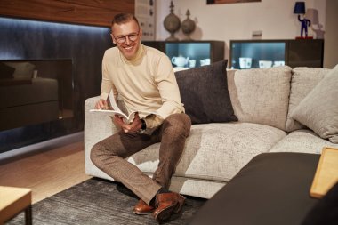 Yakışıklı, orta yaşlı, şık giyinmiş, gözlüklü, evde dinlenip dergi okuyan bir adam.. 